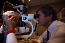 Augenoptiker untersucht Patientenaugen mit Spaltlampe in Klinik — Stockfoto
