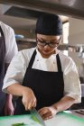Chef feminino cortando legumes na cozinha no restaurante — Fotografia de Stock