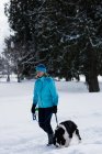 Mulher sênior andando com seu cão na paisagem nevada no inverno — Fotografia de Stock