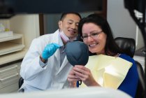 Мужчина-дантист взаимодействует с пациентом в клинике — стоковое фото