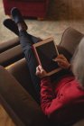Femme âgée utilisant une tablette numérique dans le salon à la maison — Photo de stock