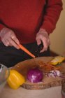 Средняя часть пожилого человека режет морковь ножом на кухне — стоковое фото