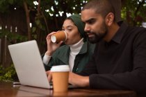 Romantic couple using laptop while having coffee at cafe — Stock Photo