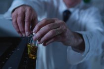 Мужчина-ученый помещает медицинские флаконы на лабораторную машину в лаборатории — стоковое фото