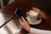 Primo piano della donna che utilizza il telefono cellulare nel caffè — Foto stock