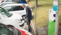 Seitenansicht: Mann lädt Elektroauto an Ladestation — Stockfoto