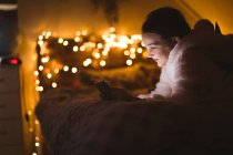 Посміхається дівчина, використовуючи цифровий планшетний проти Різдвяні вогні — стокове фото