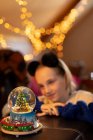 Девушка смотрит на снежный шар рождественской елки дома — стоковое фото