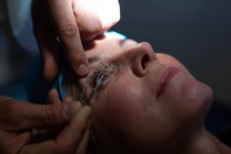 Primer plano del optometrista examinando los ojos del paciente con equipo de prueba ocular en la clínica - foto de stock