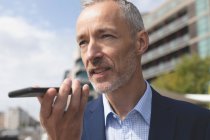 Close-up of businessman talking on mobile phone in city — Stock Photo