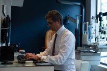 Вид сбоку оптометриста с помощью настольного компьютера в клинике — стоковое фото