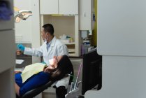 Чоловічий стоматолога, вивчаючи леді пацієнта в клініку — стокове фото