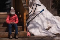 Mädchen benutzt Mobiltelefon im Winter an einem sonnigen Tag — Stockfoto