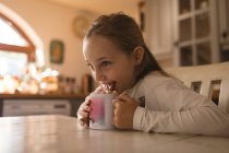 Smiling girl licking the cookie on the cup — Stock Photo