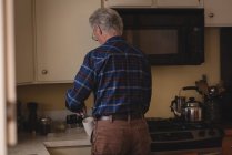 Старший мужчина готовит кофе на кухне дома — стоковое фото