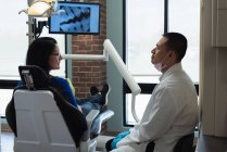 Dentista masculino interagindo com paciente na clínica — Fotografia de Stock