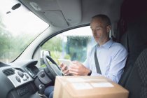 Side view of delivery man using digital tablet in delivery van — Stock Photo