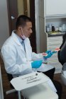 Vue latérale dentiste masculin tenant des dents artificielles en clinique — Photo de stock