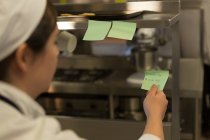 Chef feminino verificando ordem na cozinha no restaurante — Fotografia de Stock