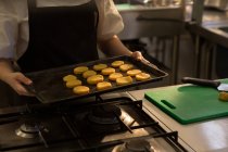 Шеф-повар держит поднос с печеньем на кухне дома — стоковое фото
