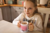 Sorrindo menina segurando uma xícara de marshmallows — Fotografia de Stock