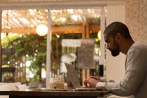 Вид збоку людини, що використовує ноутбук у кафе — стокове фото