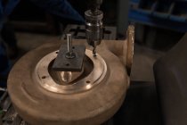 Taladro de prensa de primer plano y pieza de metal en el taller - foto de stock
