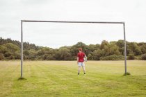 Вид спереду футболіста, що стоїть з футбольним м'ячем у полі — стокове фото