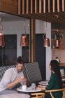 Empresario y empresaria sentados en cafetería en oficina - foto de stock
