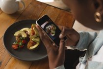 Woman taking picture of food in cafe — Stock Photo