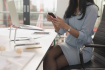 Mittelschicht weiblicher Führungskräfte mit Handy am Tisch im Büro — Stockfoto