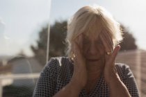 Старша жінка, що страждає від головного болю в саду — стокове фото