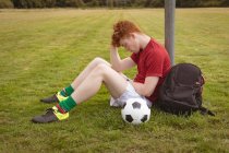 Joven futbolista relajándose en el campo - foto de stock
