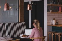 Вид сзади на деловую женщину, работающую на ноутбуке в кафетерии в офисе — стоковое фото