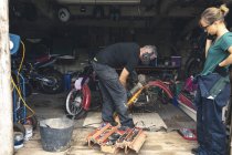 Mecânico usando moedor na garagem de reparação — Fotografia de Stock