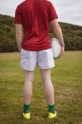 Visão traseira do jogador de rugby de pé com bola de rugby no campo — Fotografia de Stock