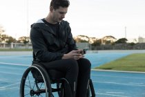 Junge Behindertensportlerin nutzt Handy in Sportstätte — Stockfoto