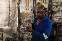 Кузнец в мастерской проверяет лезвие для резки металла — стоковое фото