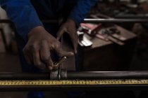 Gros plan du forgeron mesurant la tige de métal dans l'atelier — Photo de stock