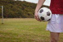 Sezione centrale del giocatore di calcio in piedi con pallone da calcio in campo — Foto stock