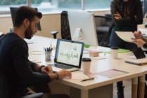 Empresário revisando o gráfico de vendas no laptop no escritório — Fotografia de Stock