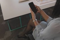 Executivo feminino usando telefone celular na mesa no escritório — Fotografia de Stock
