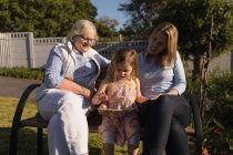 Famiglia multi-generazione in cerca di album fotografico in giardino in una giornata di sole — Foto stock
