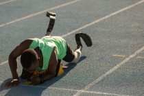 Atleta discapacitado preparándose para la carrera en pista de atletismo - foto de stock