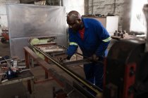 Attentive blacksmith measuring metal rod in workshop — Stock Photo