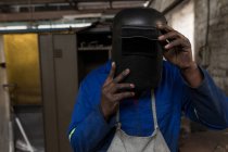 Крупный план кузнеца в сварочном шлеме в мастерской — стоковое фото