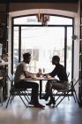 Vista lateral de la pareja mirándose en la cafetería - foto de stock