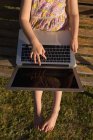 Sobrecarga de menina usando laptop no jardim em um dia ensolarado — Fotografia de Stock