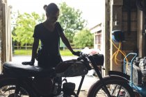 Mechanikerin steht neben Motorrad in Garage — Stockfoto