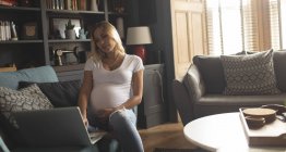 Femme enceinte utilisant un ordinateur portable à la maison — Photo de stock